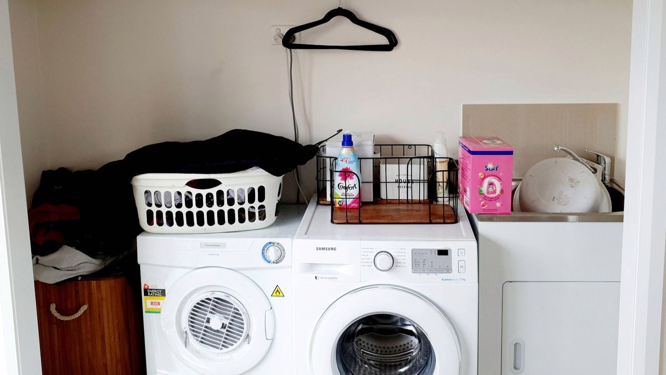 A laundry with a washing machine, a dryer and sink with cabinet underneath it, in there.