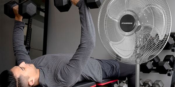 man working out with weights and fan in the room also