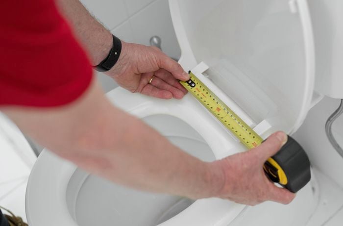 Measure the length from mounting holes to the toilet bowl's front edge 