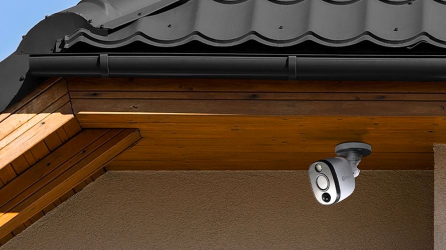 Security camera under the timber eave of a house exterior