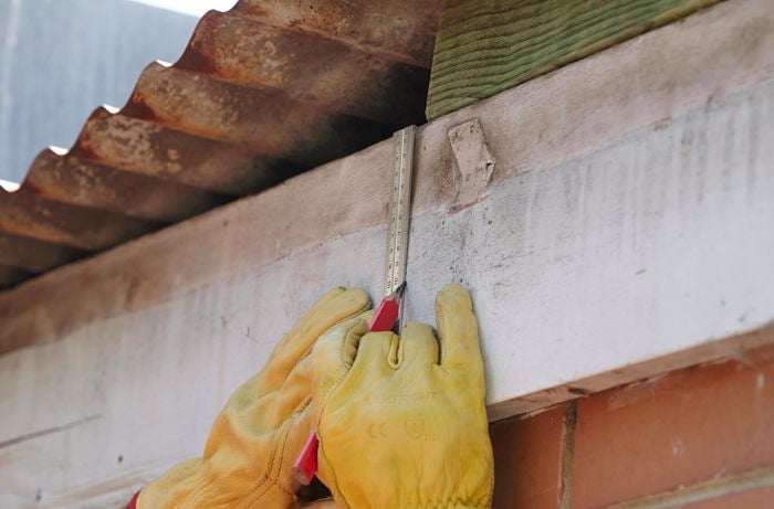 A person measuring a line on a fascia board