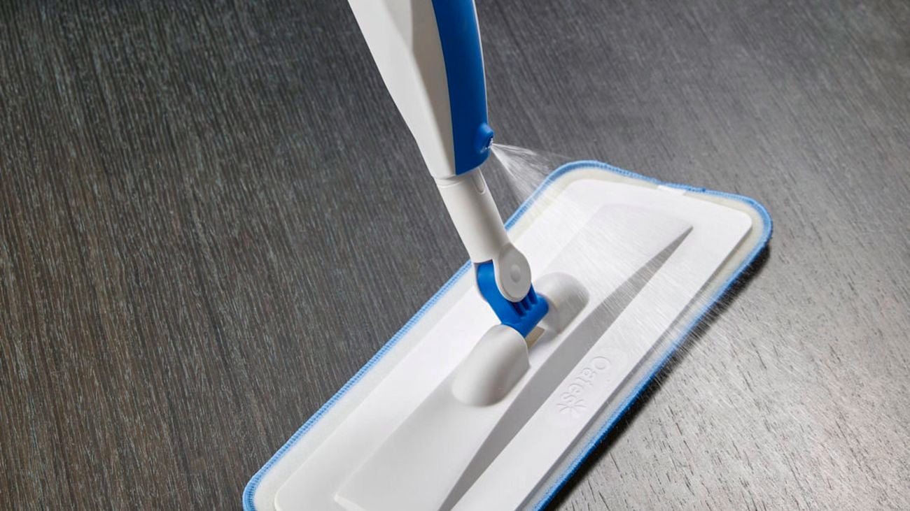 Close up of Oates Spray Mop spraying a dark wood floor.