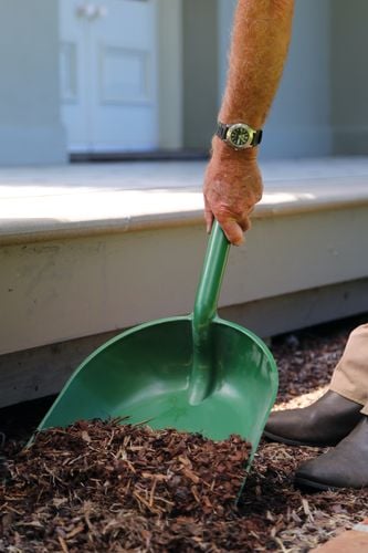 A shovel being used to spread tanbark