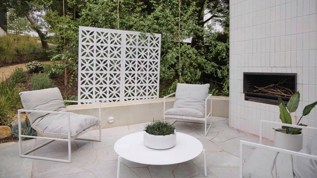 A cozy patio featuring elegant white furniture and a warm fireplace, perfect for relaxation and gatherings.