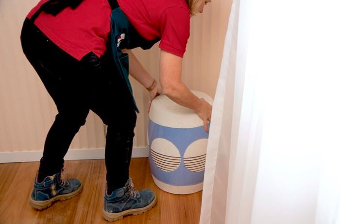 A person positioning a comfortable stool in the corner of the room. 