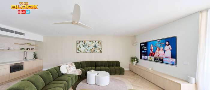 Contemporary living room featuring curved olive-green sofas, matching armchairs, a wall-mounted TV, ceiling fan and light timber cabinetry.