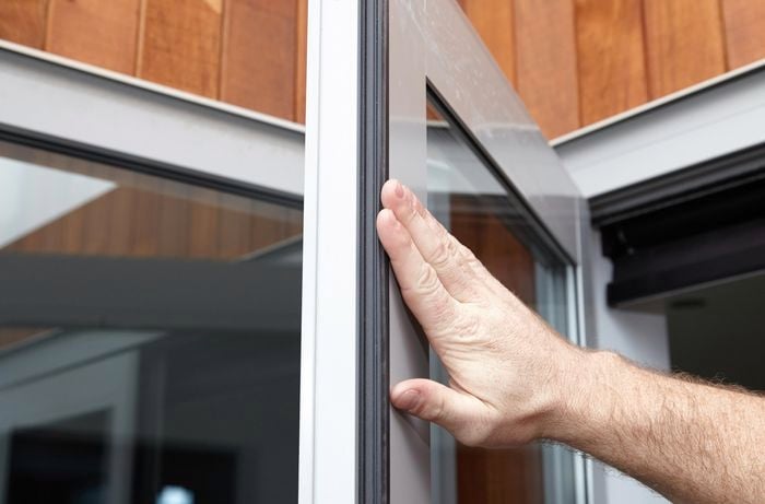 Close up of a hand pressed against the sealing of an open glass door