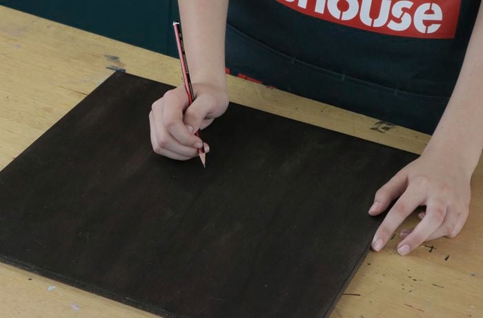 Person with pencil and sheet of stained plywood