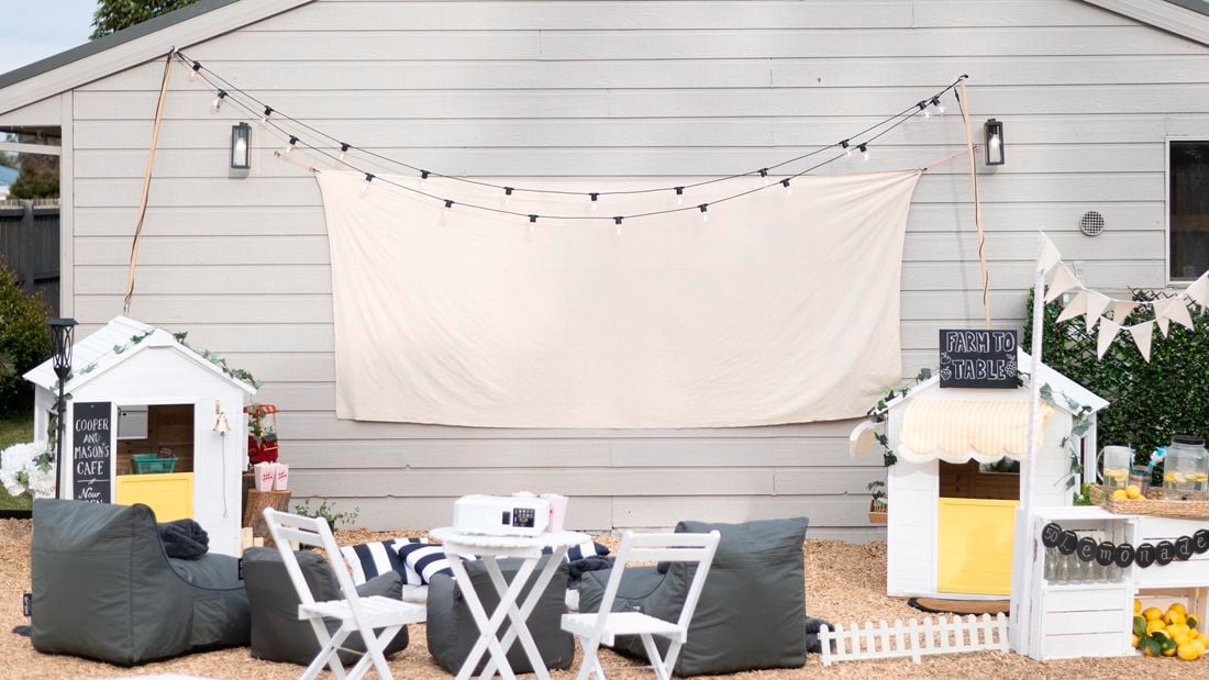 Outdoor furniture in front of a wall with canvas screen and fairy lights