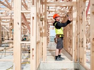 Trade person using a hammer on a house timber frame