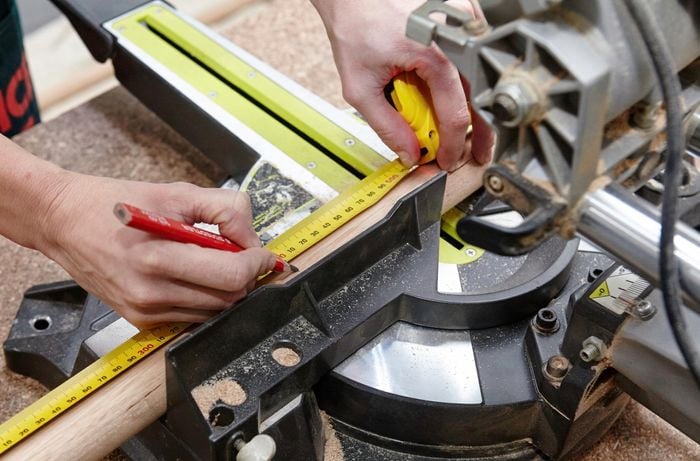 A piece of dowel being marked for cutting with a pencil and tape measure
