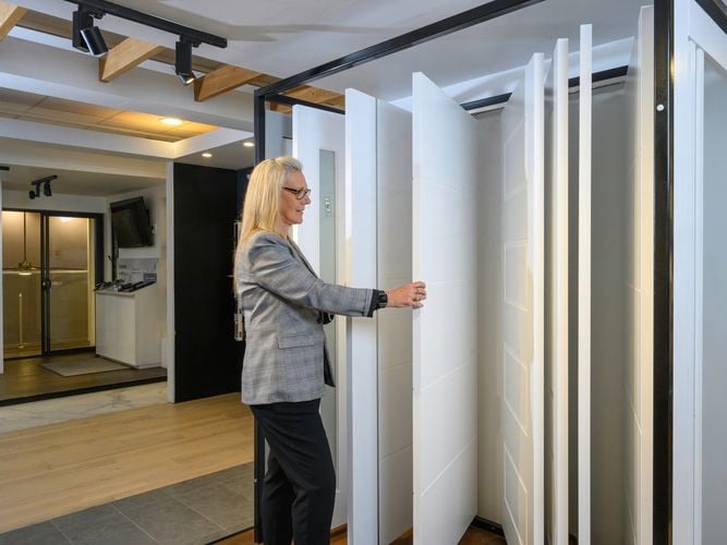 A lady with different styles of doors hanging in a display area.