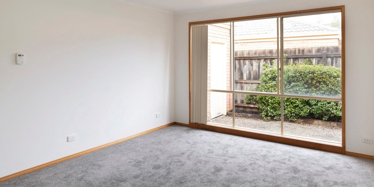 Empty room with cream walls and grey carpet.