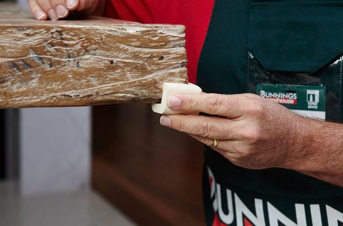 A person fitting a corner protector to a timber bench