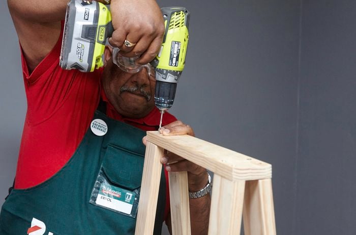 A person fitting a top piece of timber to A-frame legs