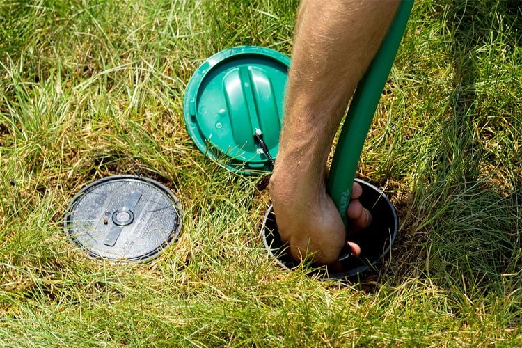Person connecting hose to lawn sprinkler system