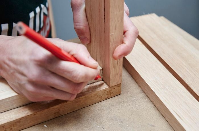 Person marking joins of two pieces of timber with pencil