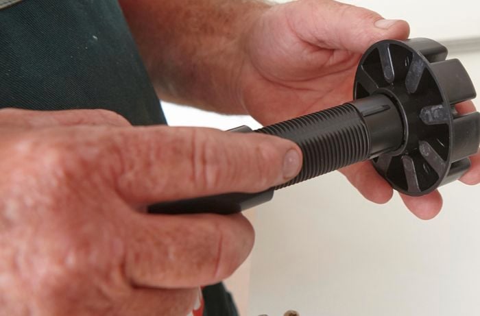 Person holding black adjustable cabinet leg