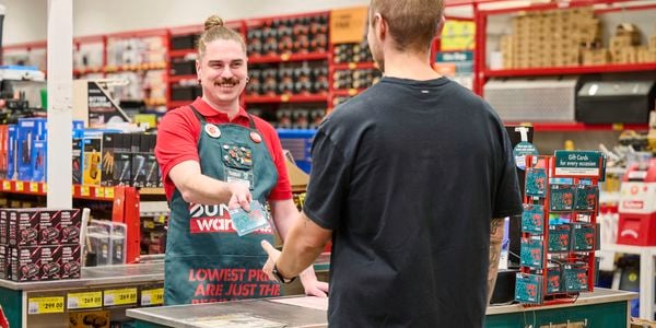 Male Bunnings team member assisting customer with gift card at warehouse
