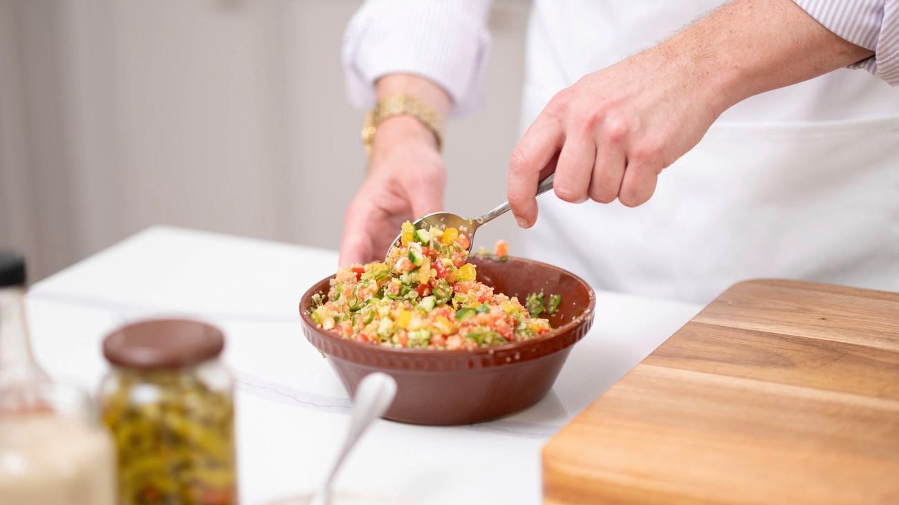 Mixing a bowl of tabouli salad with a spatula.