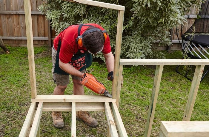 A wooden frame for a chicken coop being nailed together by a Bunnings team member with a nail gun