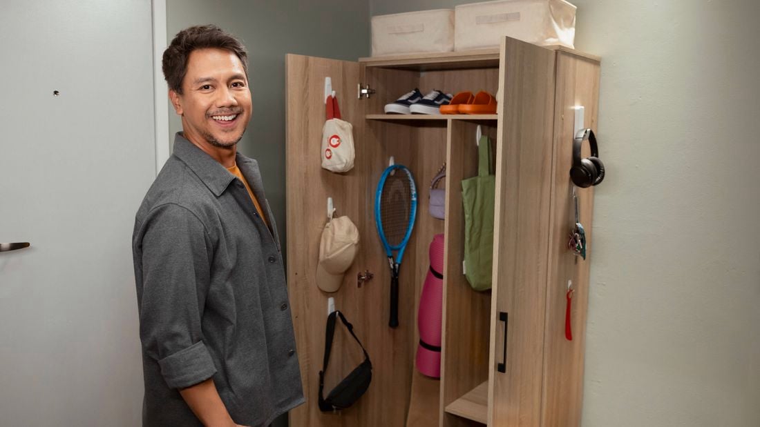 A gentleman standing in front of a cupboard with items in it.