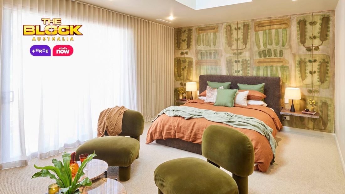  Bedroom with patterned green wallpaper, earthy bedding, and green velvet chairs.