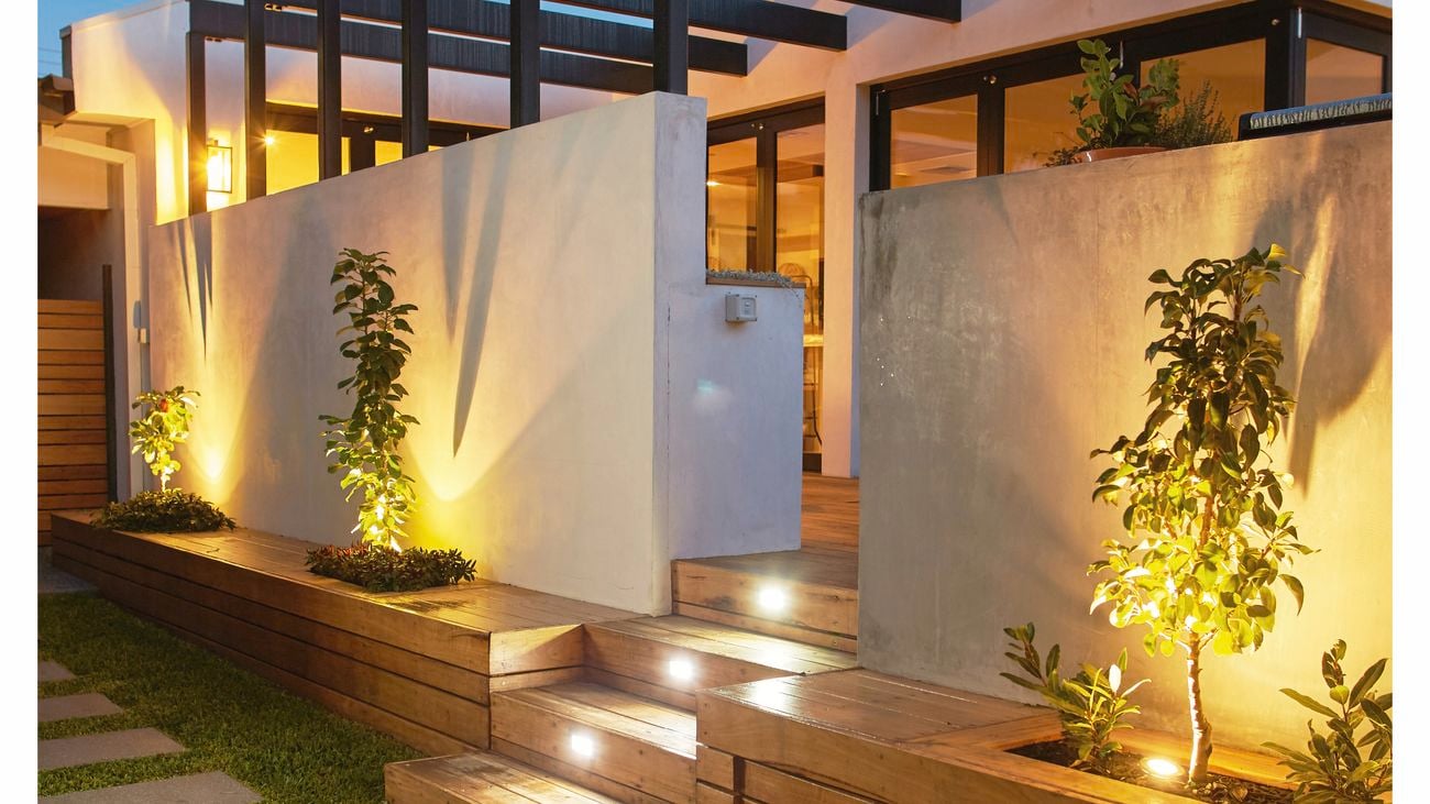 Modern house with decking and soft lighting at night time.