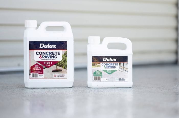 Two Dulux Concrete & Paving cleaning products are placed on a concrete surface, one for bare concrete and the other for sealed surfaces.