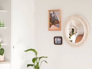A finished arrangement of framed artwork and a decorative mirror shows how picture hangers can be used to securely display different types of wall décor while minimising wall damage