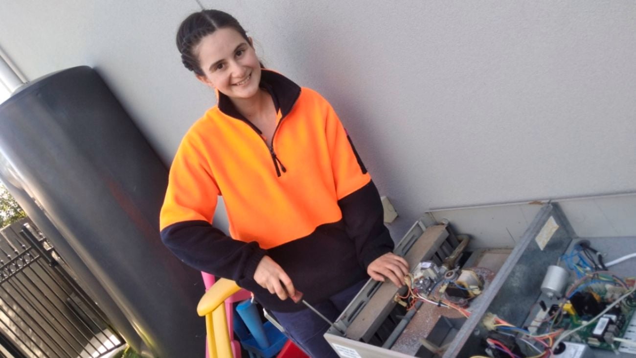 Female plumbing apprentice Holly Bromage in orange hi-vis at work.