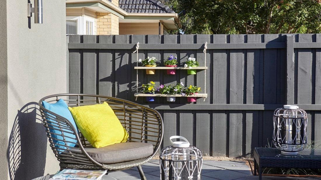 A pot plant holder with six pots hanging on a paling fence
