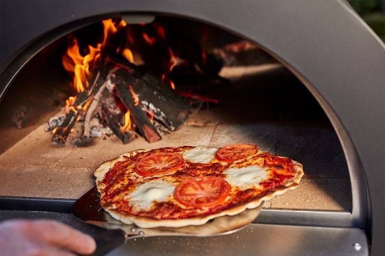 The saddest looking pizza being removed from a pizza oven