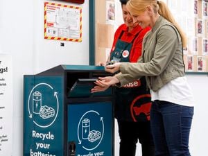 team member and customer using battery recycling bin