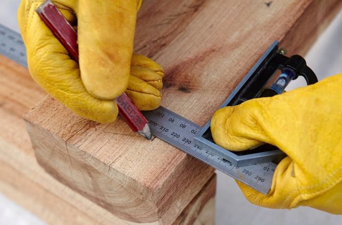 A square rule and pencil being used to mark a piece of timber for drilling