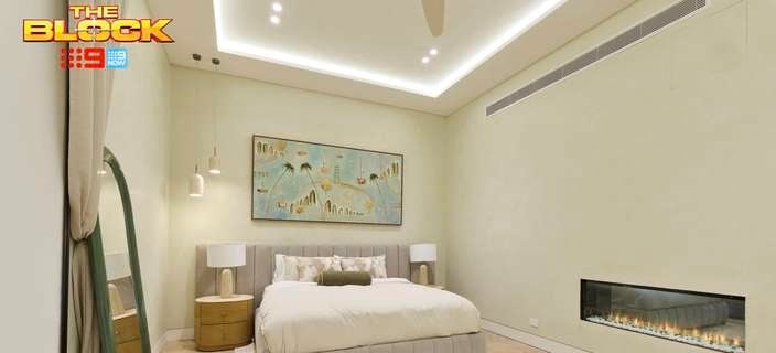 Neutral bedroom with an upholstered bed, green floor mirror, framed artwork, timber flooring, bedside tables and a long built-in fireplace.