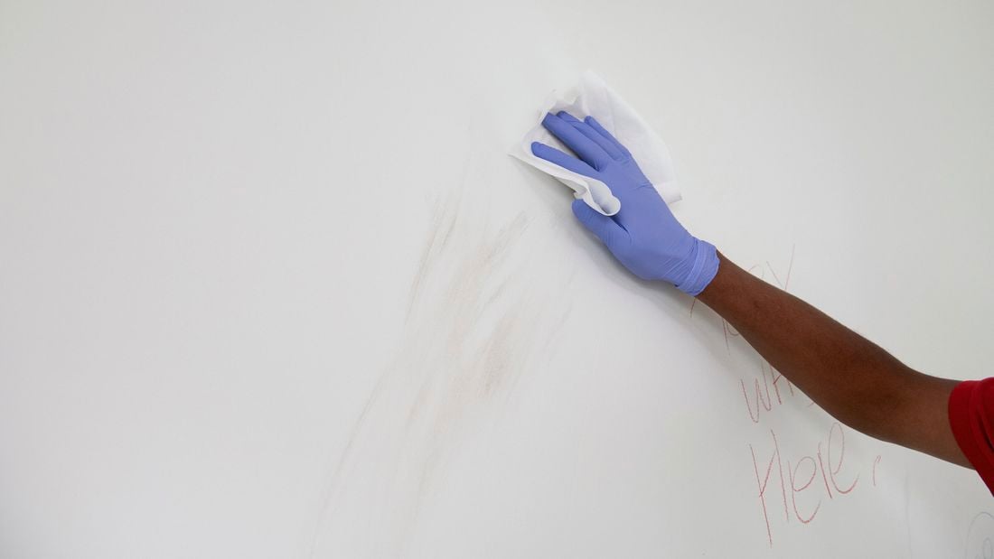 Cleaning a wall using a wipe. 