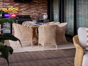 An outdoor area with a table and chairs around it in front of a barbecue.