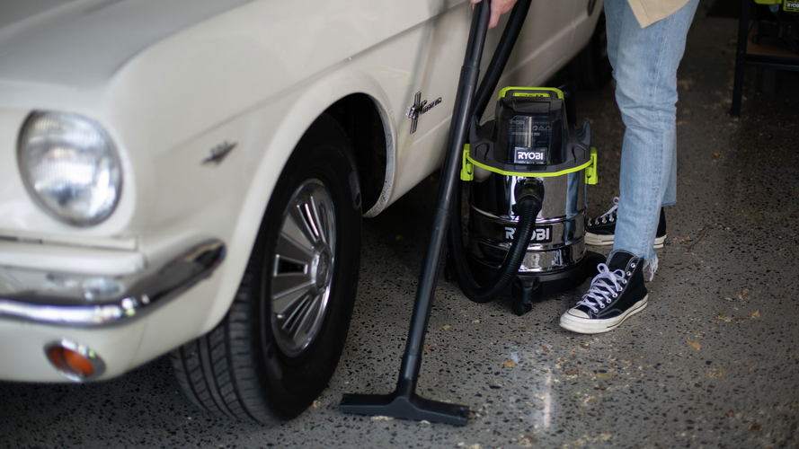 A person operating a vacuum cleaner in a garage.