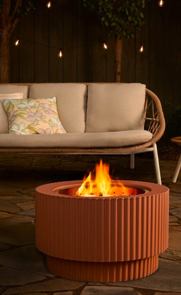 Outdoor area with an outdoor lounge, chair, table and a Fire pit on paving in it.