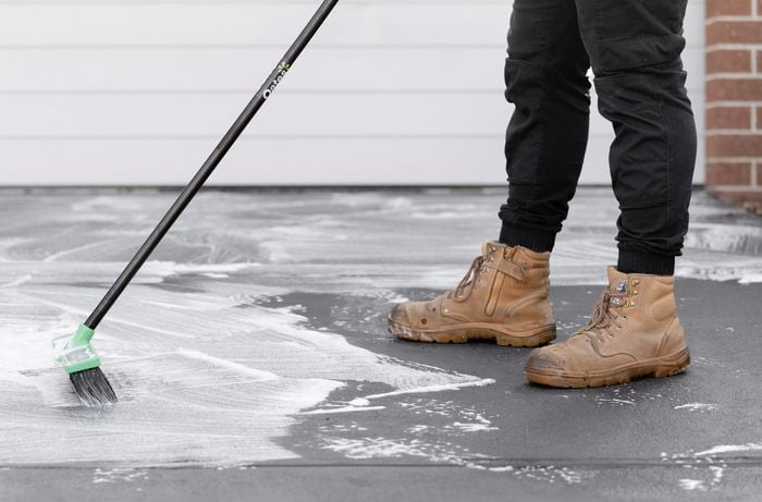A person cleaning the driveway with a broom