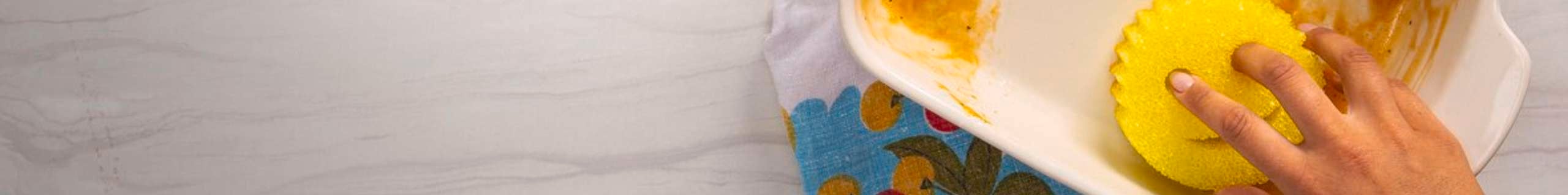 A person cleaning a messy dish with the Scrub Daddy.
