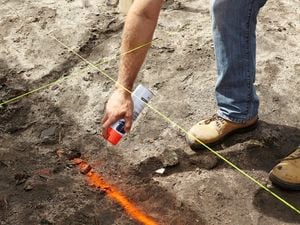 Person spray painting the ground.
