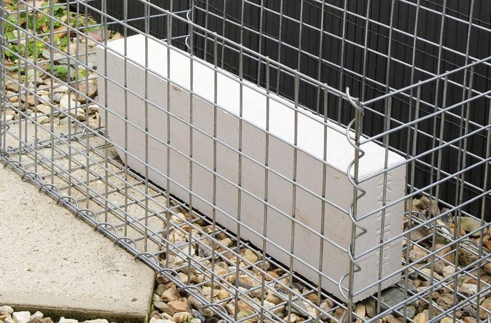A concrete block sitting inside an otherwise empty gabion cage