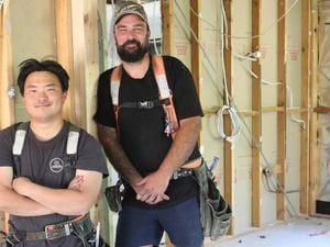 : Two tradies on a job site, one with arms crossed the other with hands in front, both smiling.