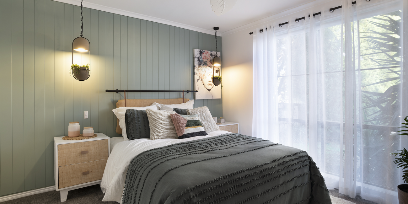 Bedroom with green wall panelling, double bed and bedside tables.