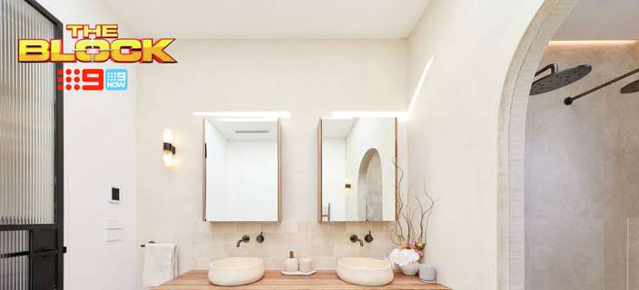 Modern bathroom with a floating timber double vanity, white vessel basins, rectangular mirrors, black tapware and an arched walk-in shower. “The Block” logo appears in the upper-left corner.