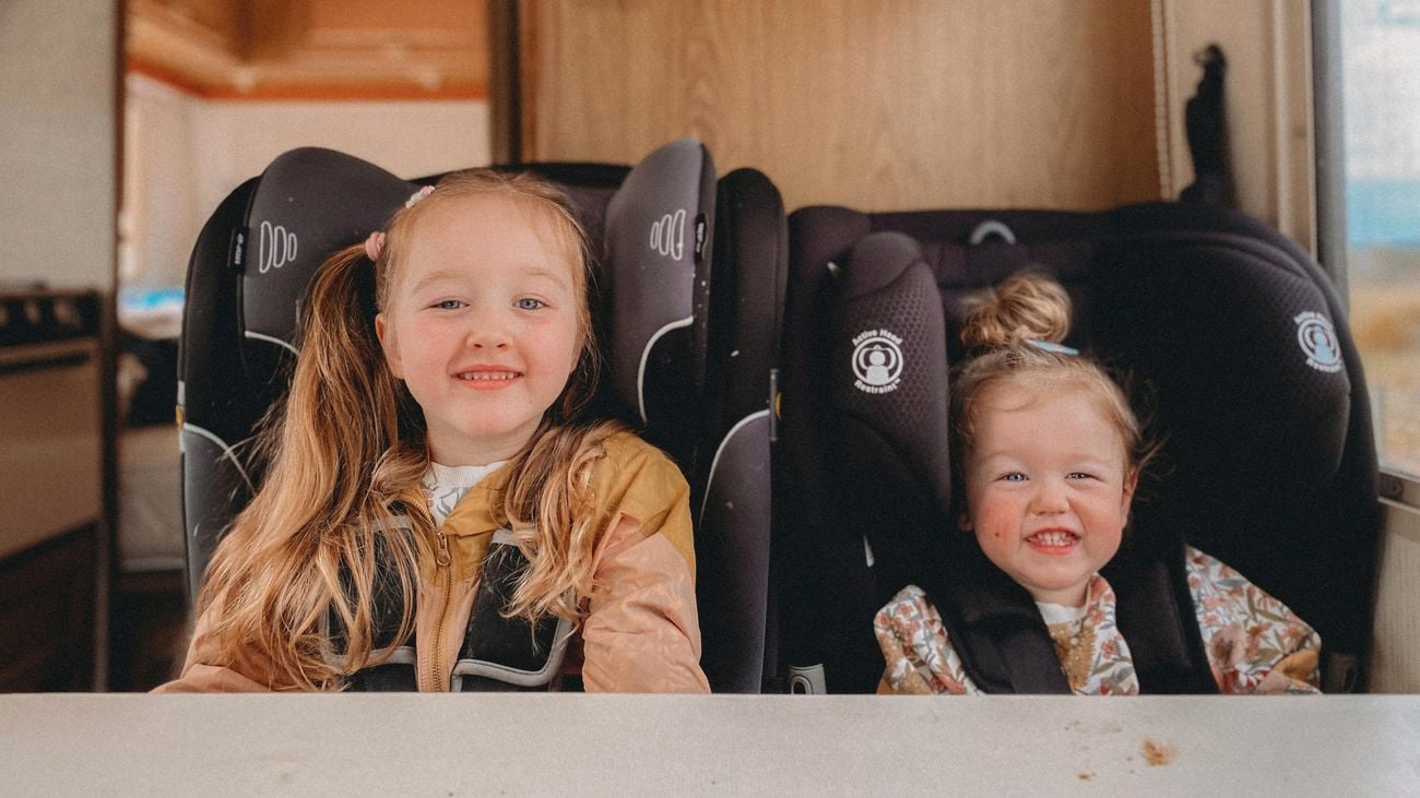 Two kids sitting in an RV, smiling.