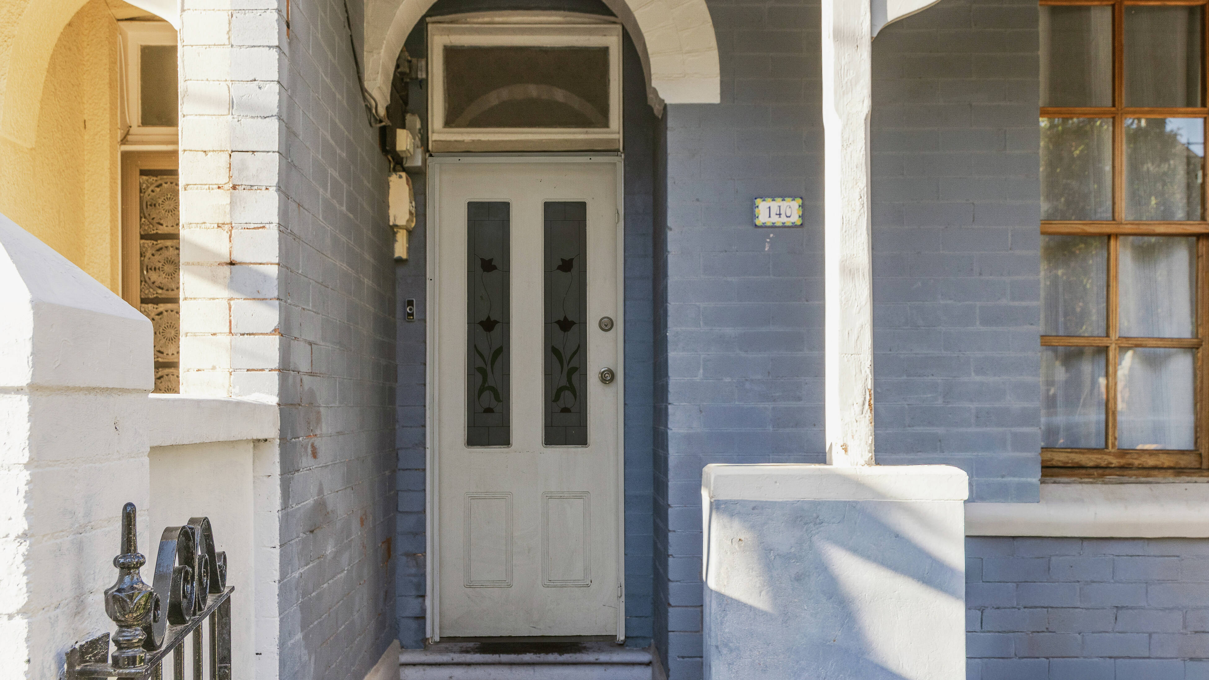 Heritage home entrance with blue brickwork and white trim.