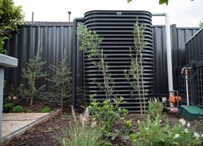 Water tank sitting in a back garden surrounded but plants.
